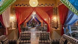 A traditional inn with a central seating area, a staircase, and patterned drapery.