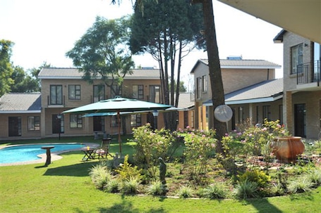 A residential property with a swimming pool, outdoor seating, and a garden.