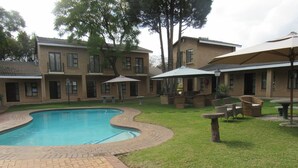 A swimming pool surrounded by a brick patio, with outdoor furniture and umbrellas. - Hoyohoyo Chartwell Lodge (Chartwell)