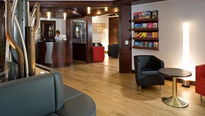 Un vestíbulo con mostrador de recepción, una zona de estar con una mesa redonda y una estantería con libros de viajes.