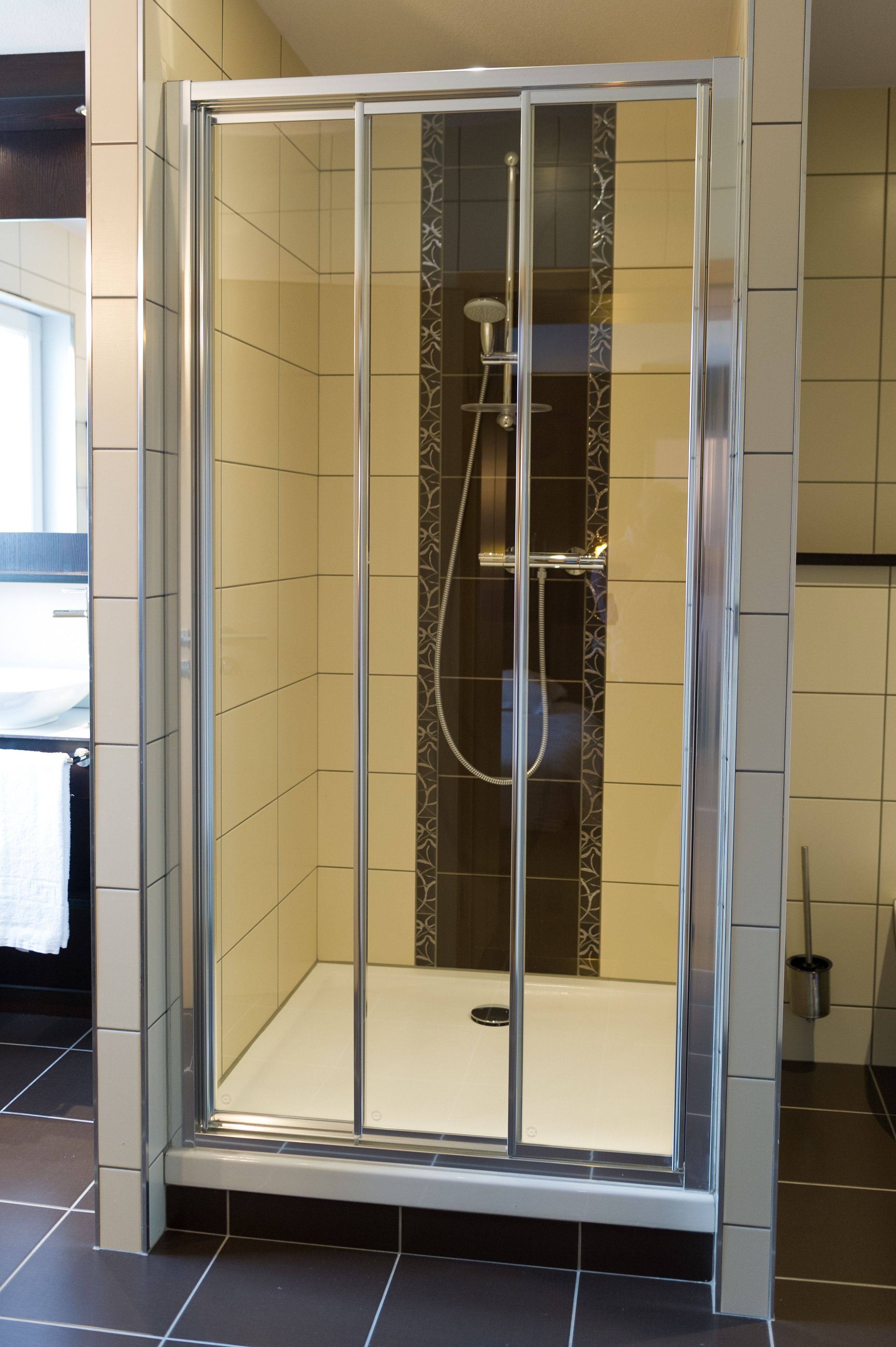 A glass-enclosed shower stall with a showerhead and control panel.