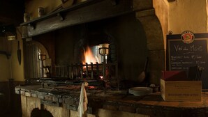 A traditional stone kitchen with a wood-burning stove, a chalkboard menu, and a bottle of Bouchard Père & Fils wine. - Auberge Le Renard'eau (Beze)