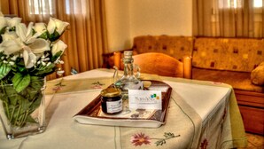 A table with a tray containing a jar and a bottle, a vase with flowers, and a business card. - Mainades Maisonettes and Studios (Andros)