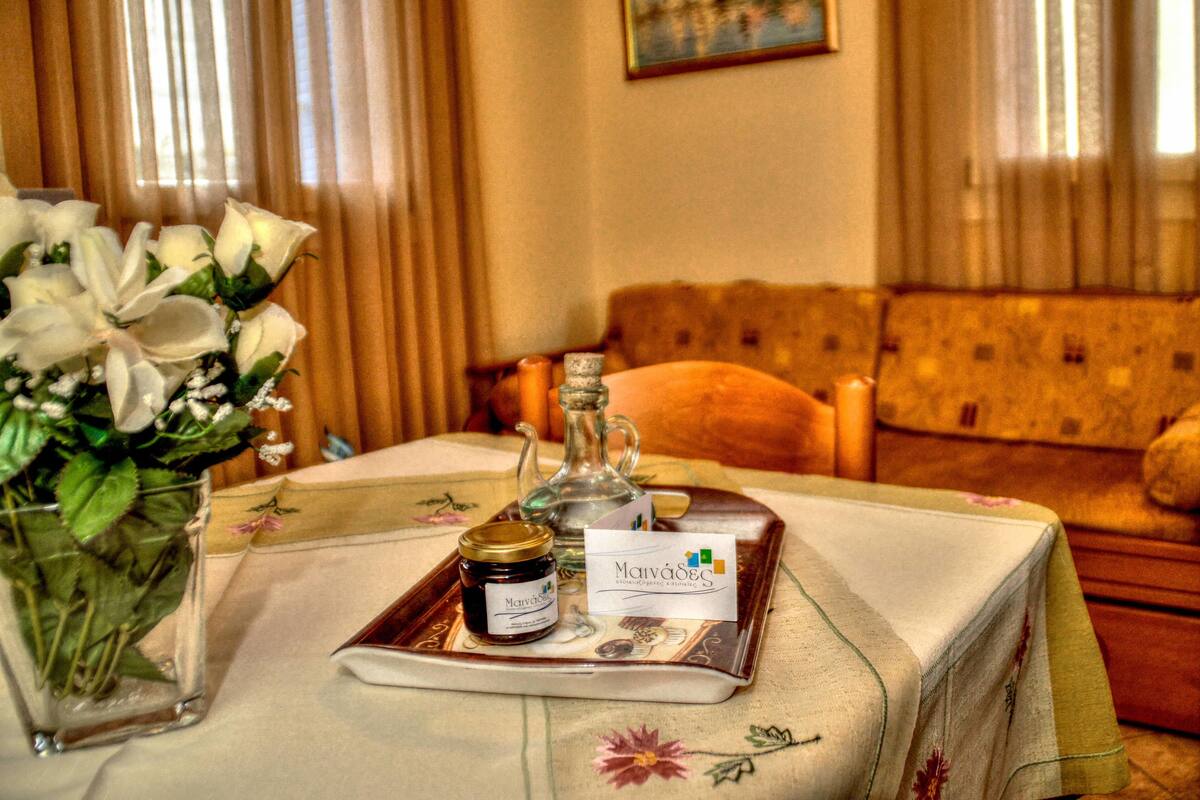 A table with a tray containing a jar and a bottle, a vase with flowers, and a business card.