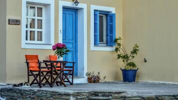 A building with a stone wall, a table with chairs, and a potted plant.