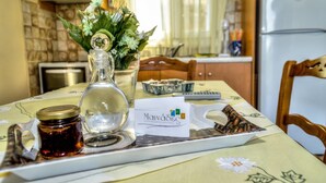 A dining table with a tray, a glass jar, a bottle, and a card. - Mainades Maisonettes and Studios (Andros)
