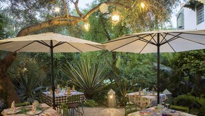 Un espace de restauration en plein air, avec des tables et des chaises, entouré d’une végétation luxuriante et d’arbres.