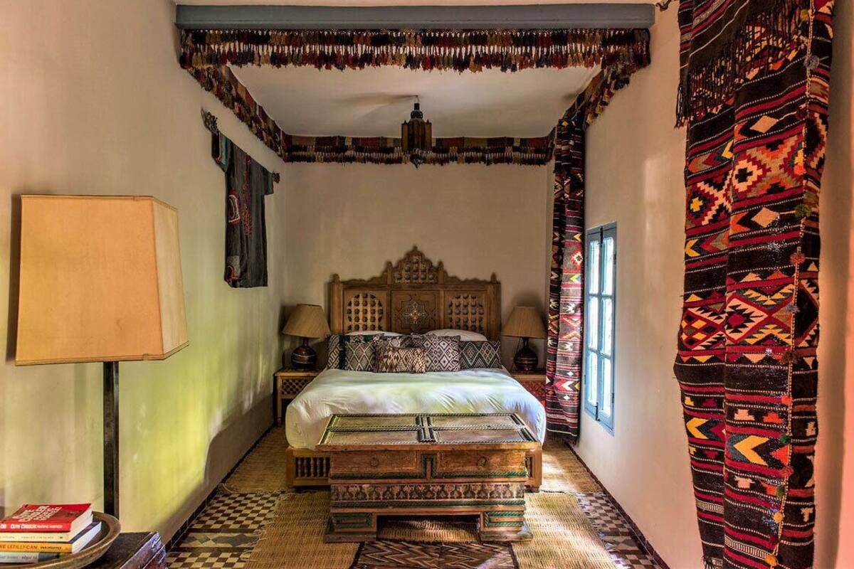 A traditional room with a bed, a lamp, and patterned textiles.