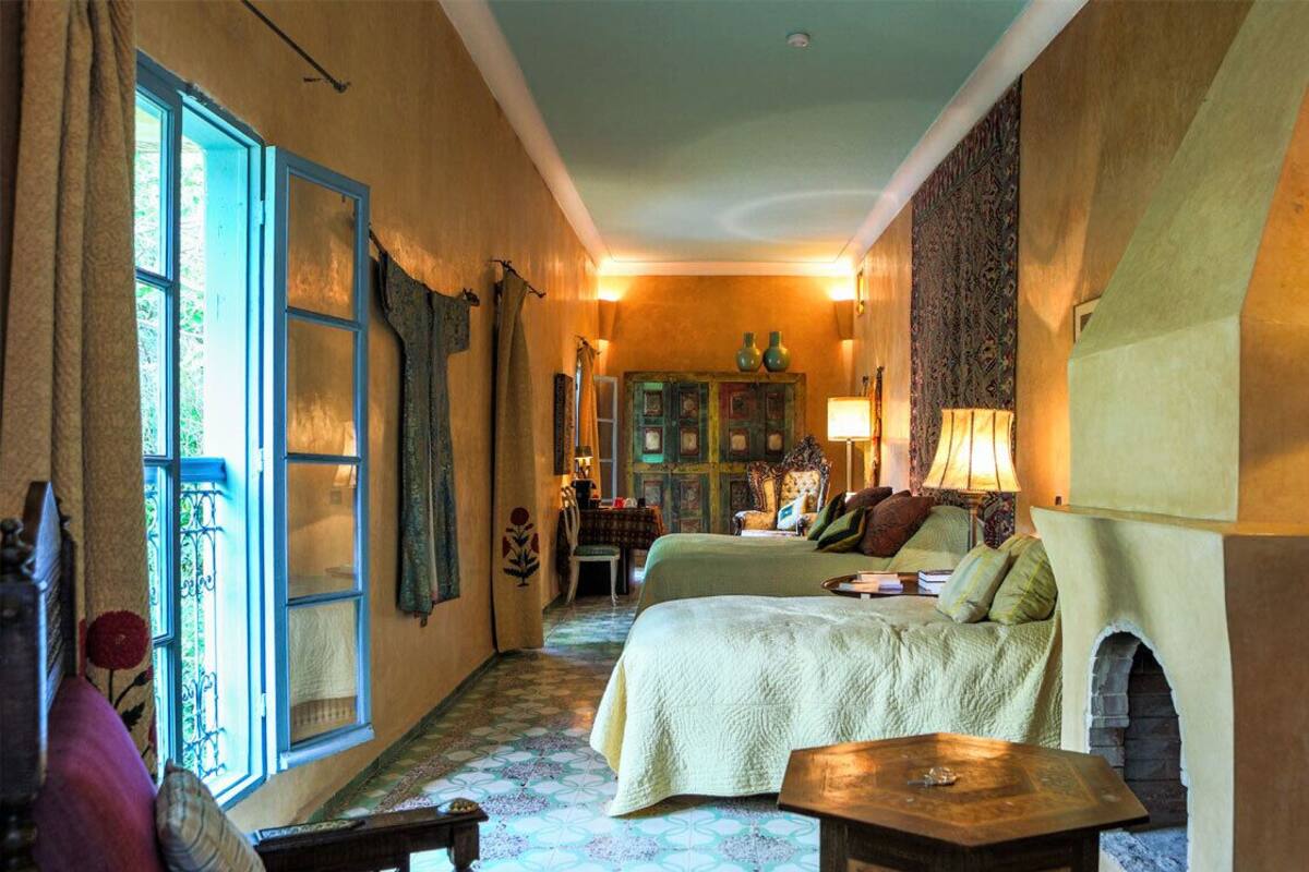 A cozy room with a bed, a table, and a fireplace.