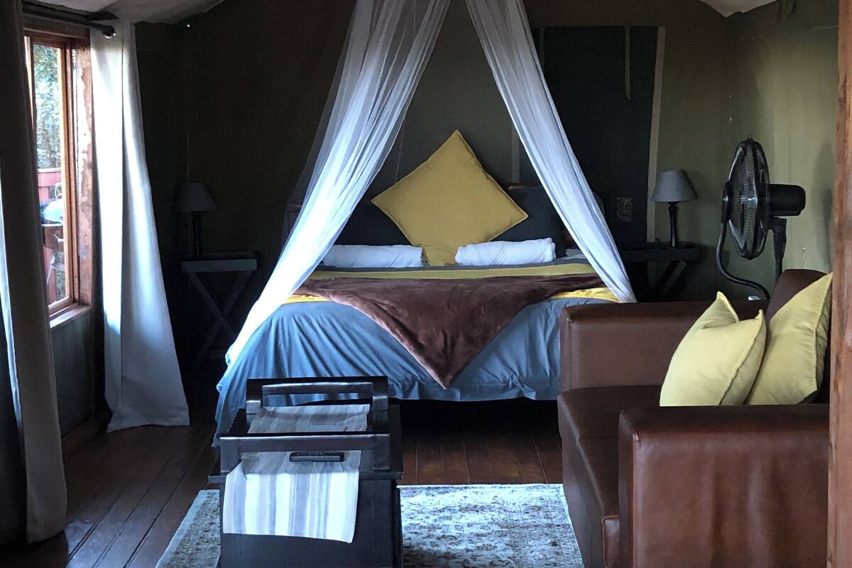 A bedroom with a bed, bedside tables, a chair, and a fan.