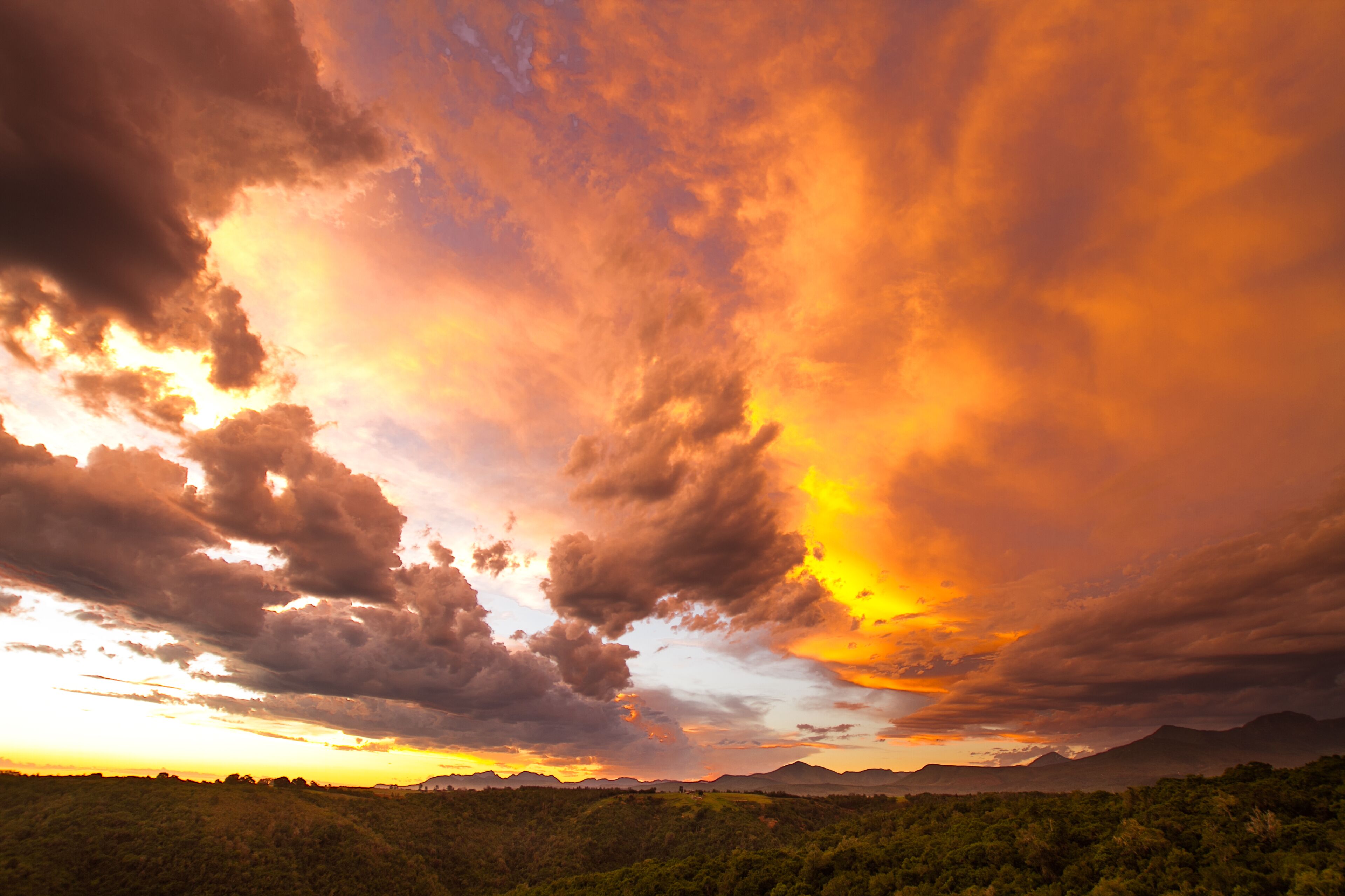 Un paisaje con una cadena montañosa a lo lejos y un cielo nublado.
