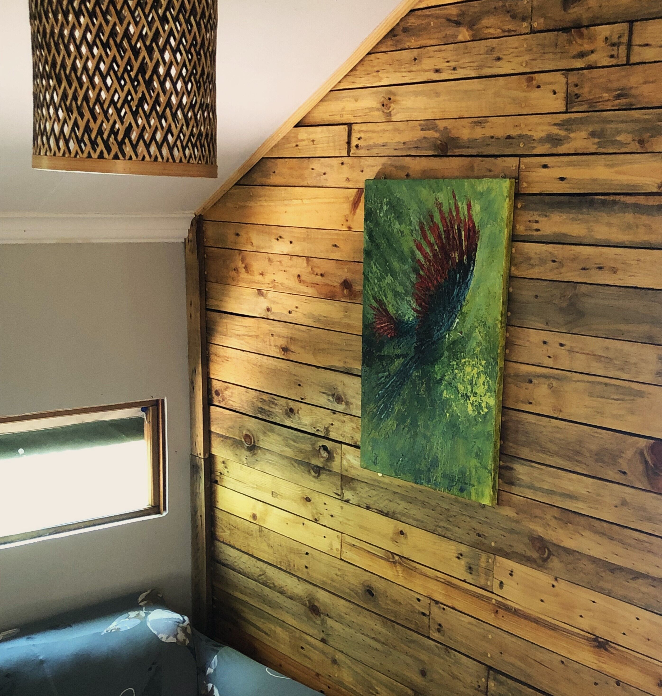 Una habitación con paredes de madera, una ventana y un cuadro.