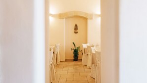 A corridor with a tiled floor, white walls, and a stone archway. - Hotel L'Arcangelo Boutique Hotel (Taranto)