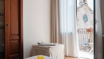 A hotel room with a bed, a table with a tray, a window with curtains, and a view of a building outside.