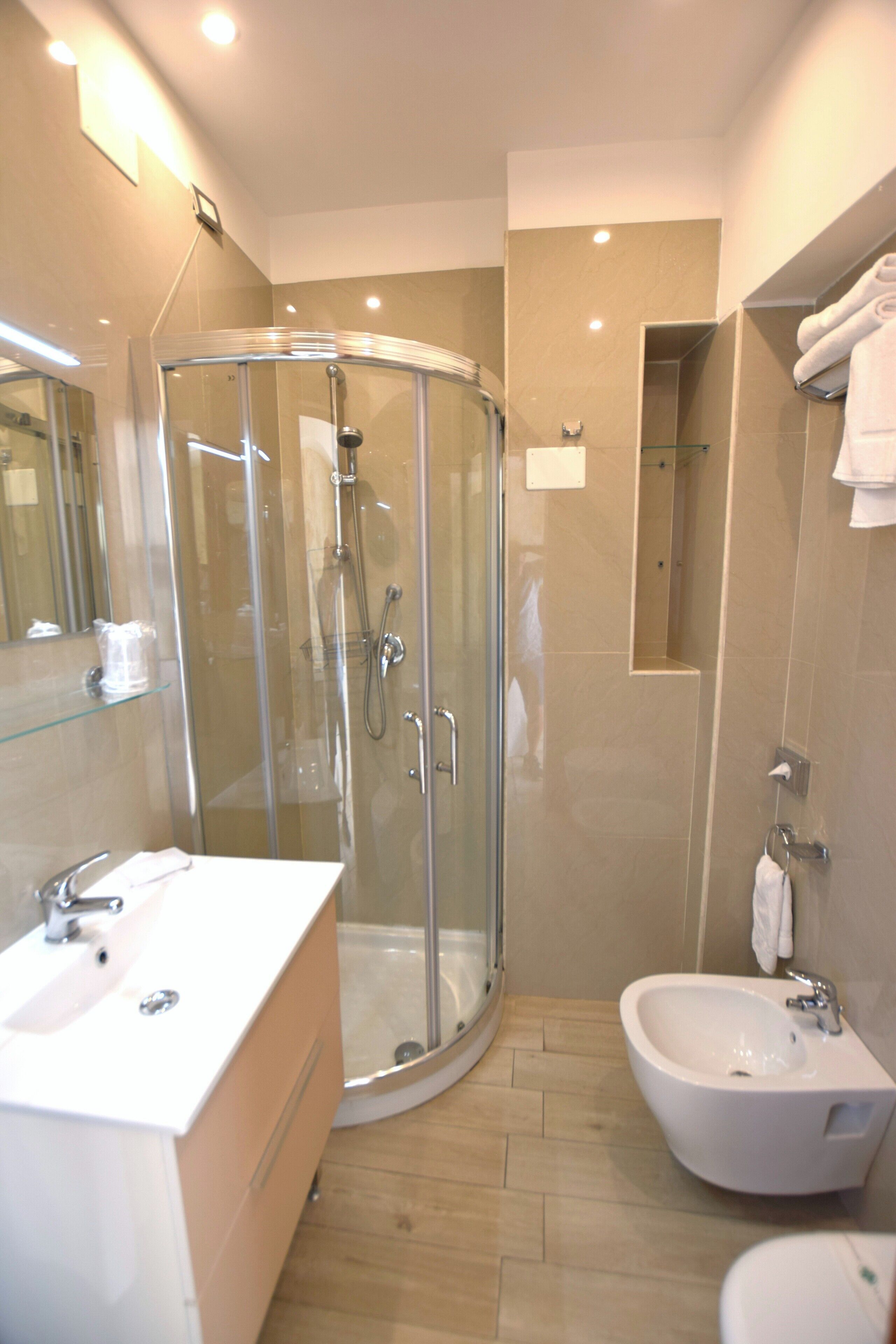 A modern bathroom with a glass-enclosed shower, a sink, and a bidet.