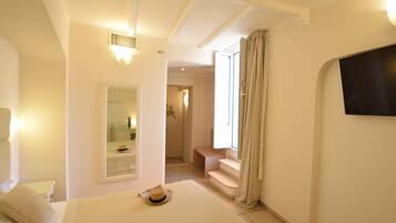 Ett hotellrum med en säng, en spegel, en tv som är monterad på väggen och en trappa som leder till ett annat rum.