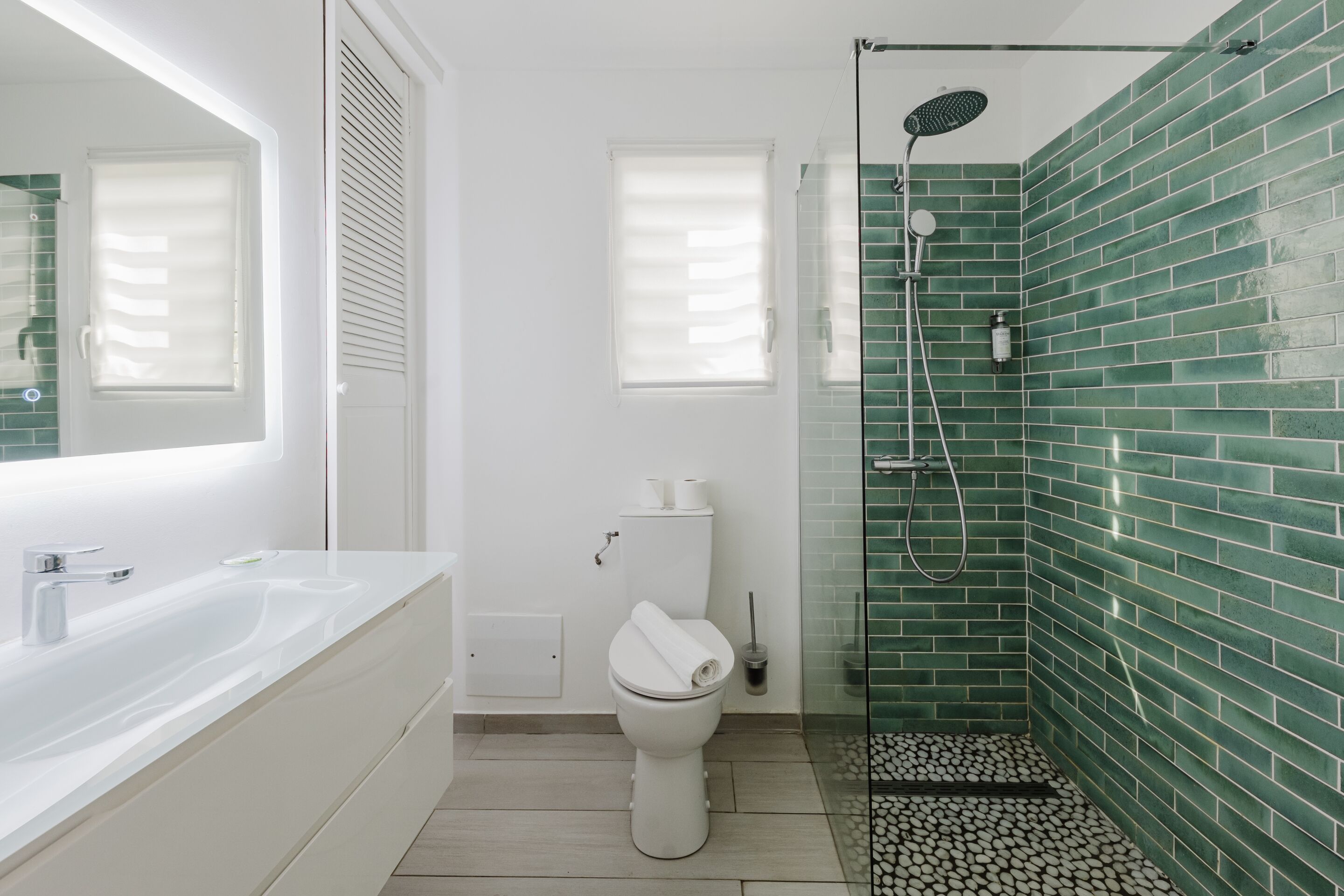 Een badkamer met een witte badkuip, toilet en douchegedeelte met groene tegels.