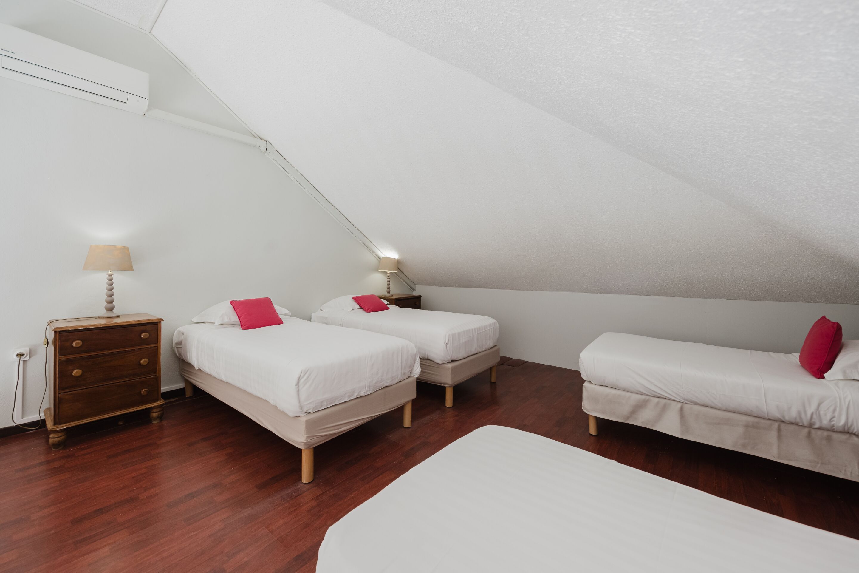 Un dormitorio con dos camas individuales, una mesita de noche de madera y una lámpara.