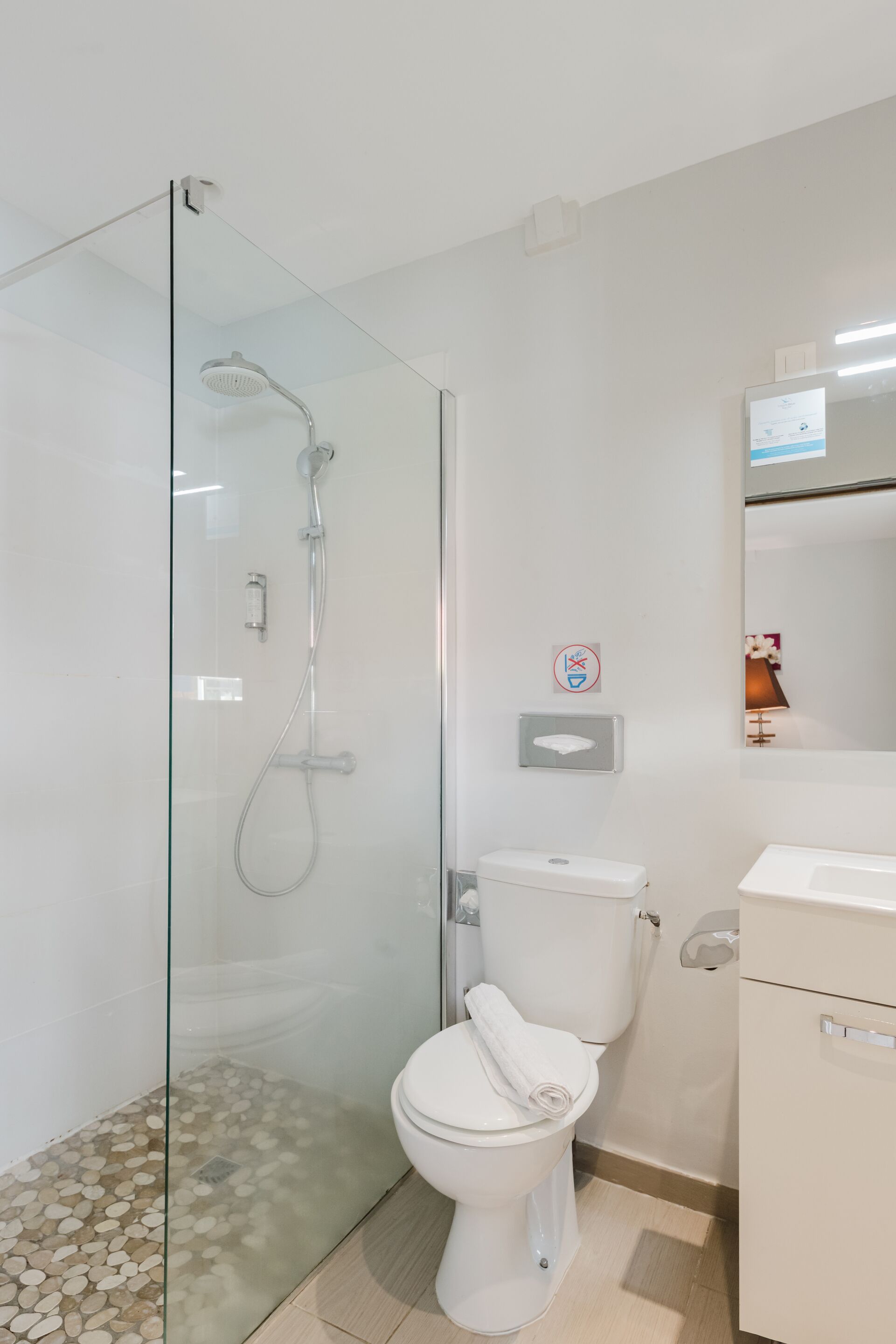 A modern bathroom with a glass-enclosed shower, a toilet, and a sink.
