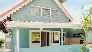 A two-story house with a teal exterior, a tiled roof, and a small porch area. - Hôtel Frégate Bleue (Le Francois)