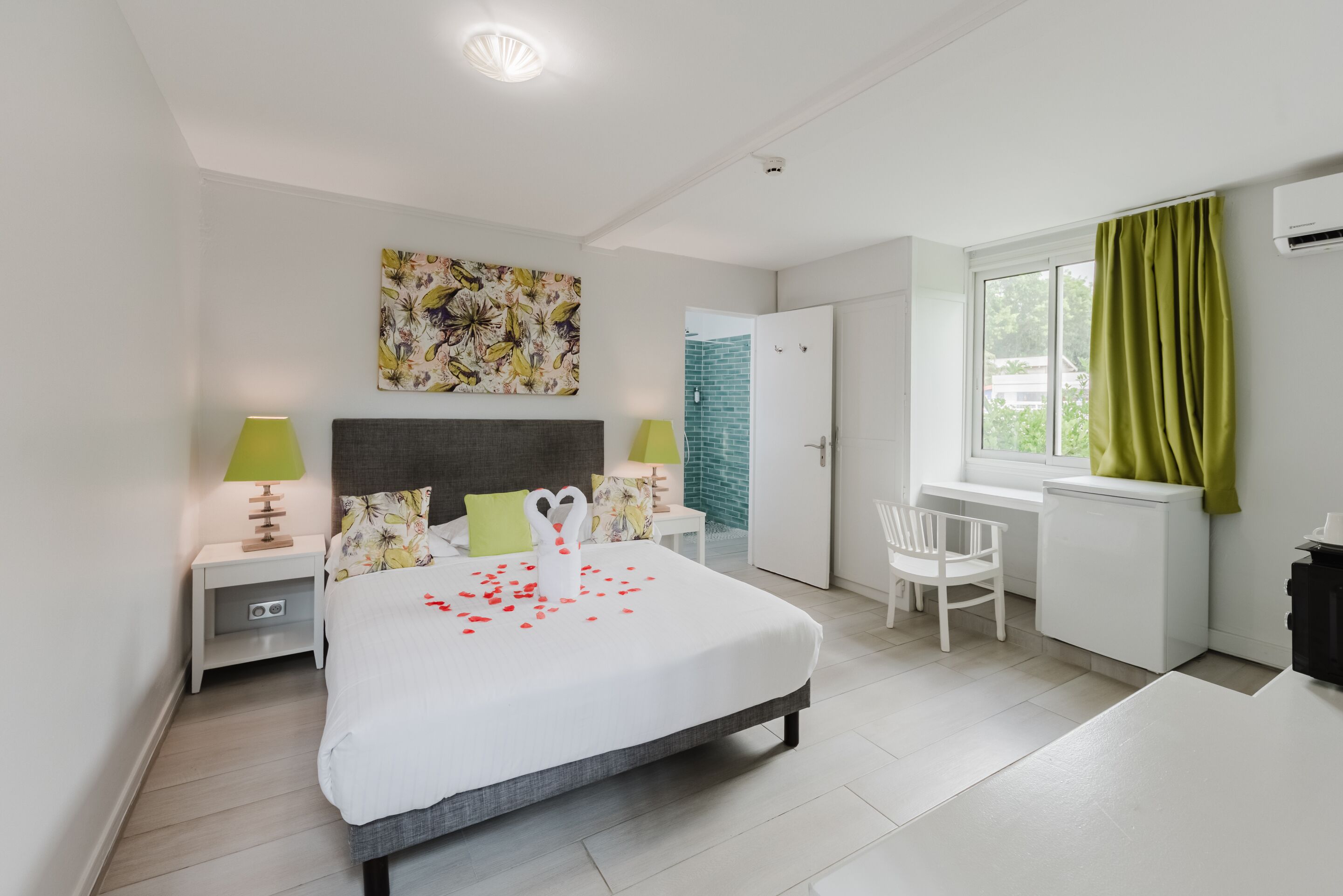 A modern bedroom with a bed, bedside tables, a desk, and a chair.