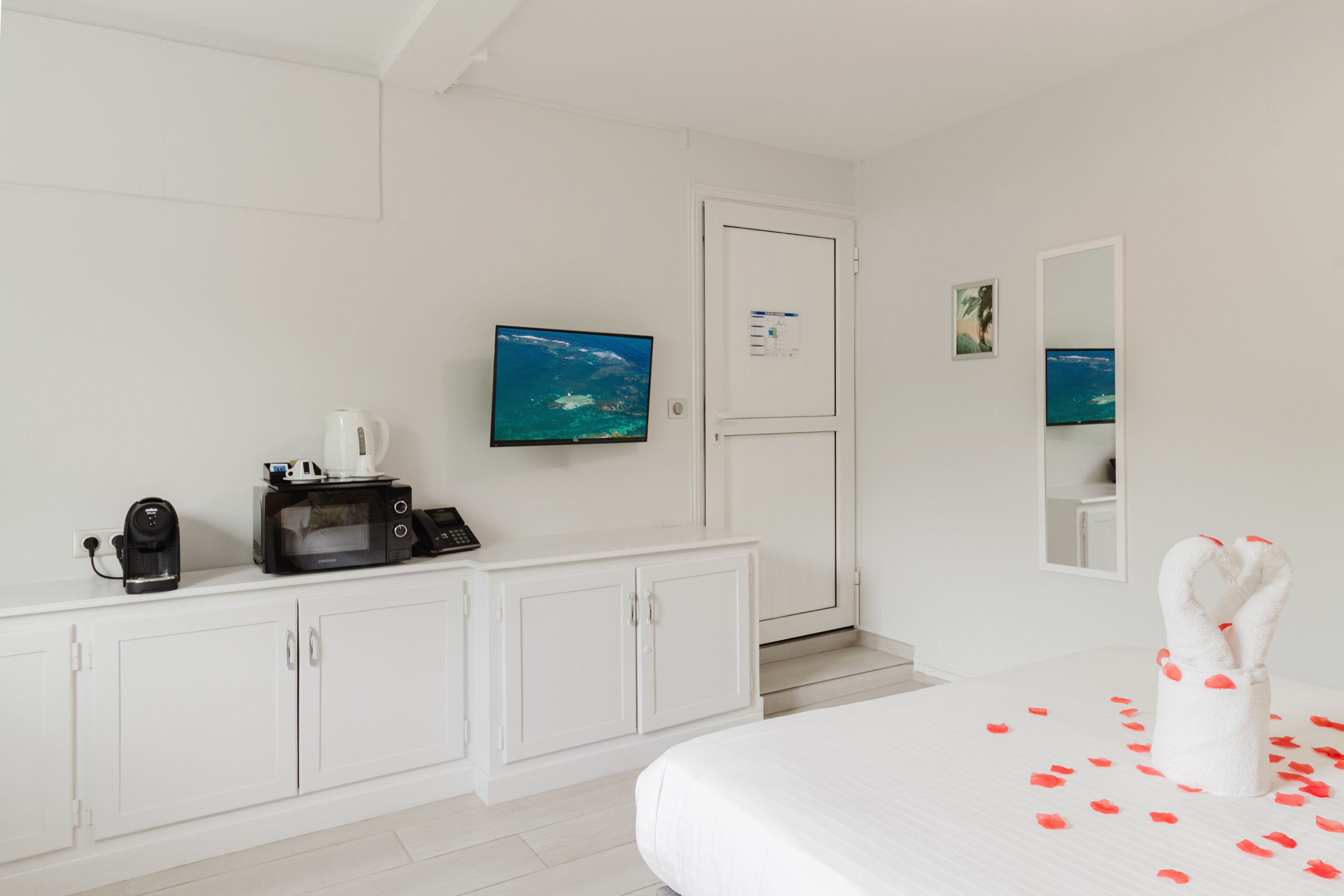 A hotel room with a bed, a TV, a coffee maker, and a cabinet.