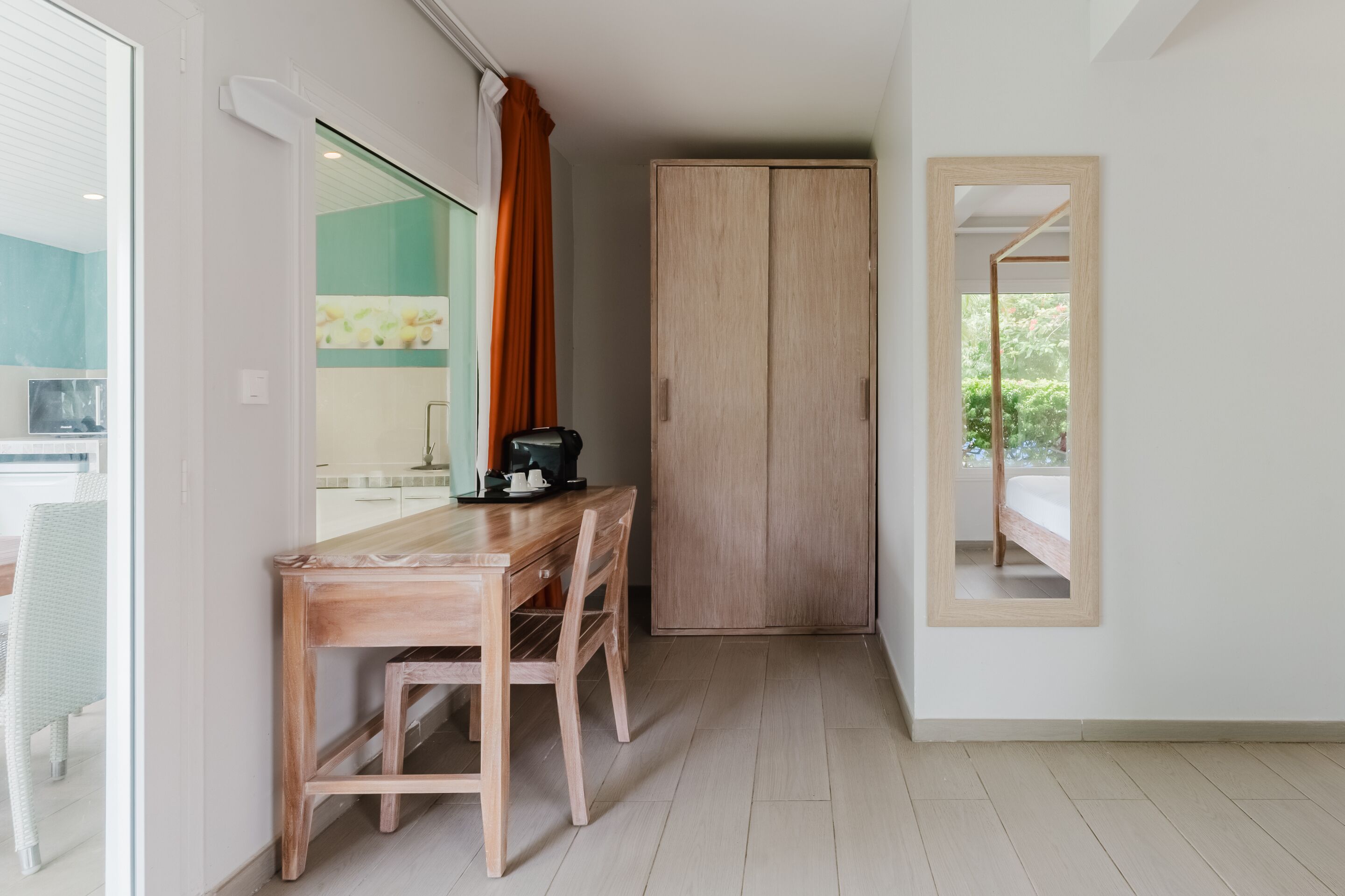 A room with a wooden desk, two chairs, a wardrobe, and a mirror on the wall.
