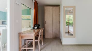 A room with a wooden desk, two chairs, a wardrobe, and a mirror on the wall.