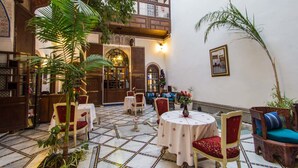 Ein traditionell eingerichteter Innenraum mit Fliesenboden, aufwendigen Möbeln und einem Balkon mit Aussicht.