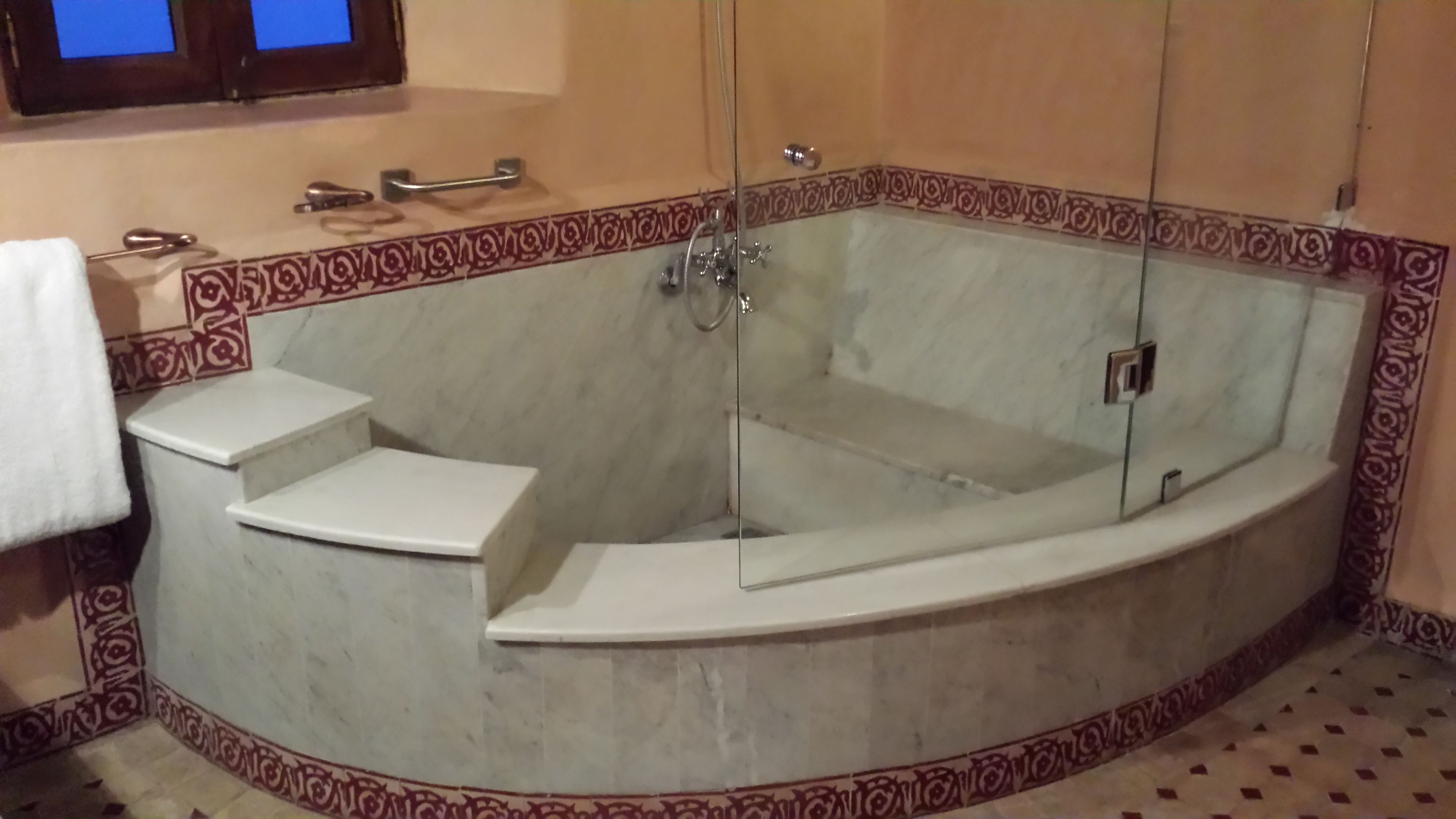 Une salle de bain avec une baignoire sur pieds, une douche à parois de verre et une serviette blanche posée sur un porte-serviettes.