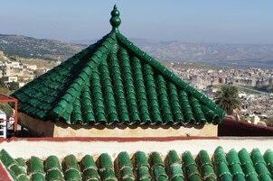 Um edifício com telhado de azulejos verdes e parapeito vermelho.