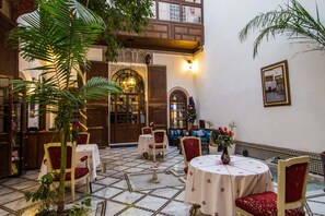 Un intérieur traditionnel avec un sol carrelé, des meubles en bois et des plantes décoratives.