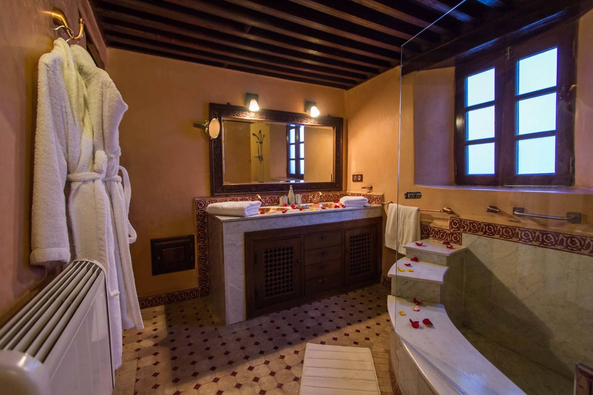 A bathroom with a large mirror, a bathtub, a sink with toiletries, and a towel rack.