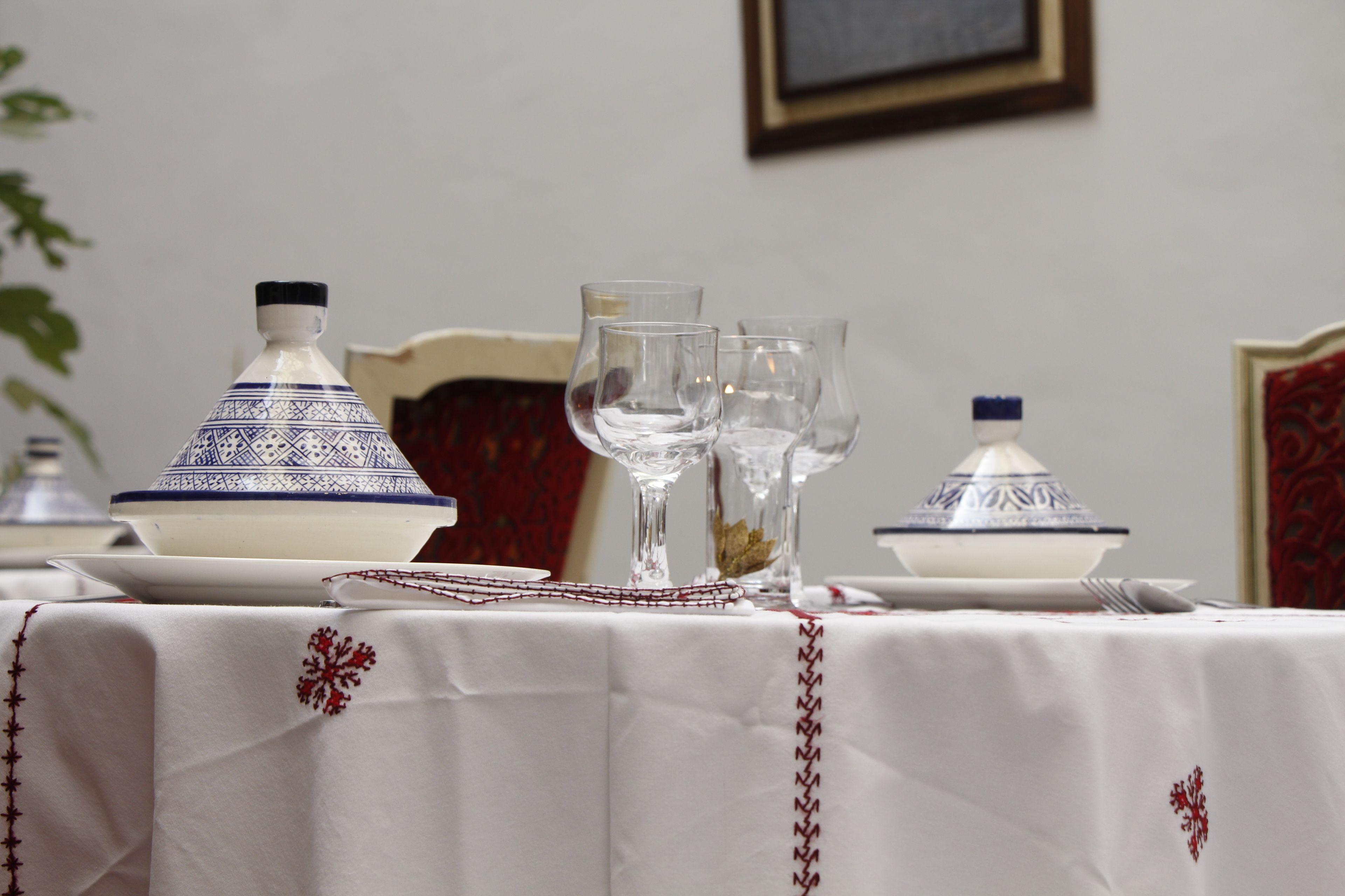 A dining table set with white tablecloth, blue and white patterned tureen, clear stemware, and a small bowl.