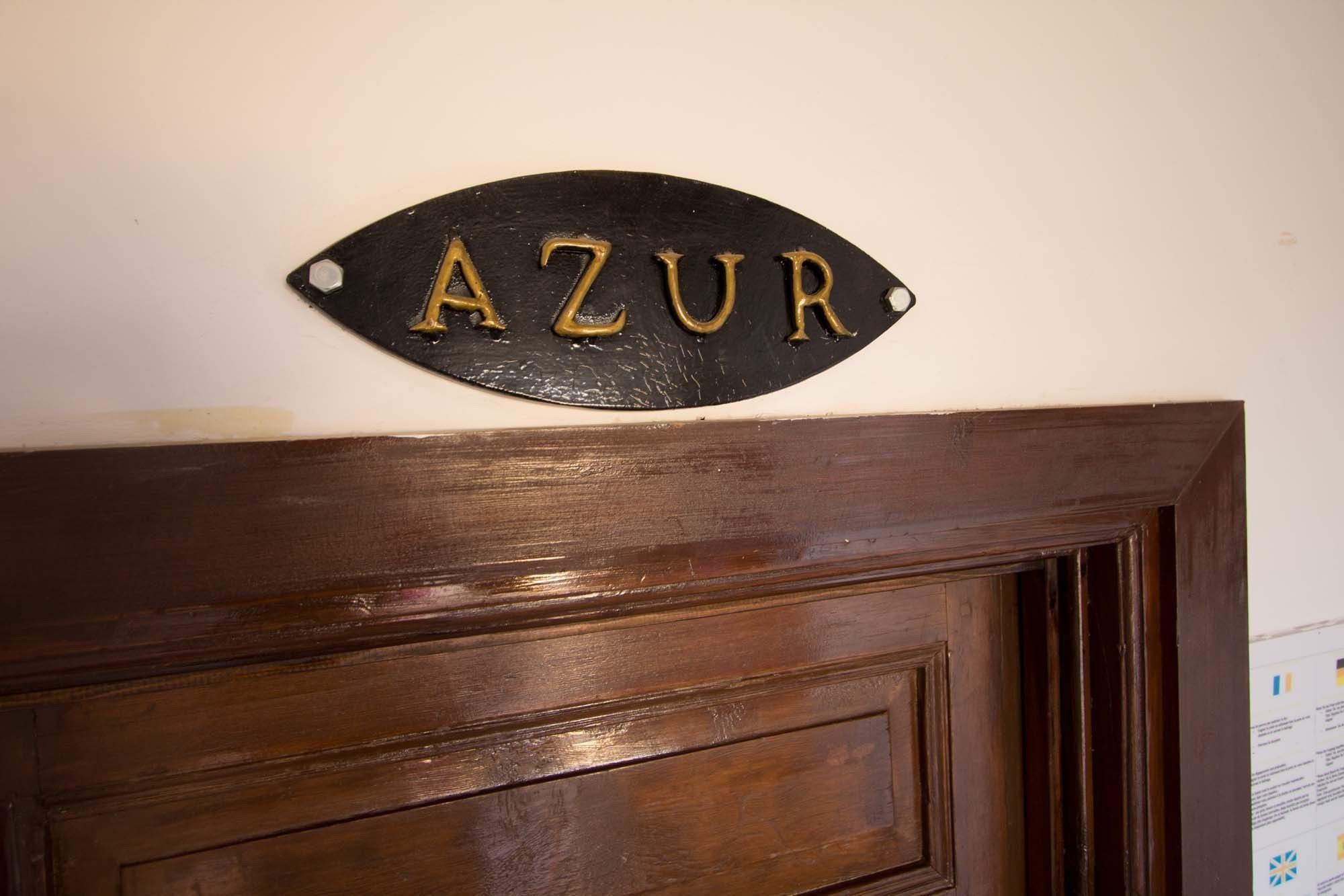 A wooden door with a black metal sign above it that reads "AZUR".