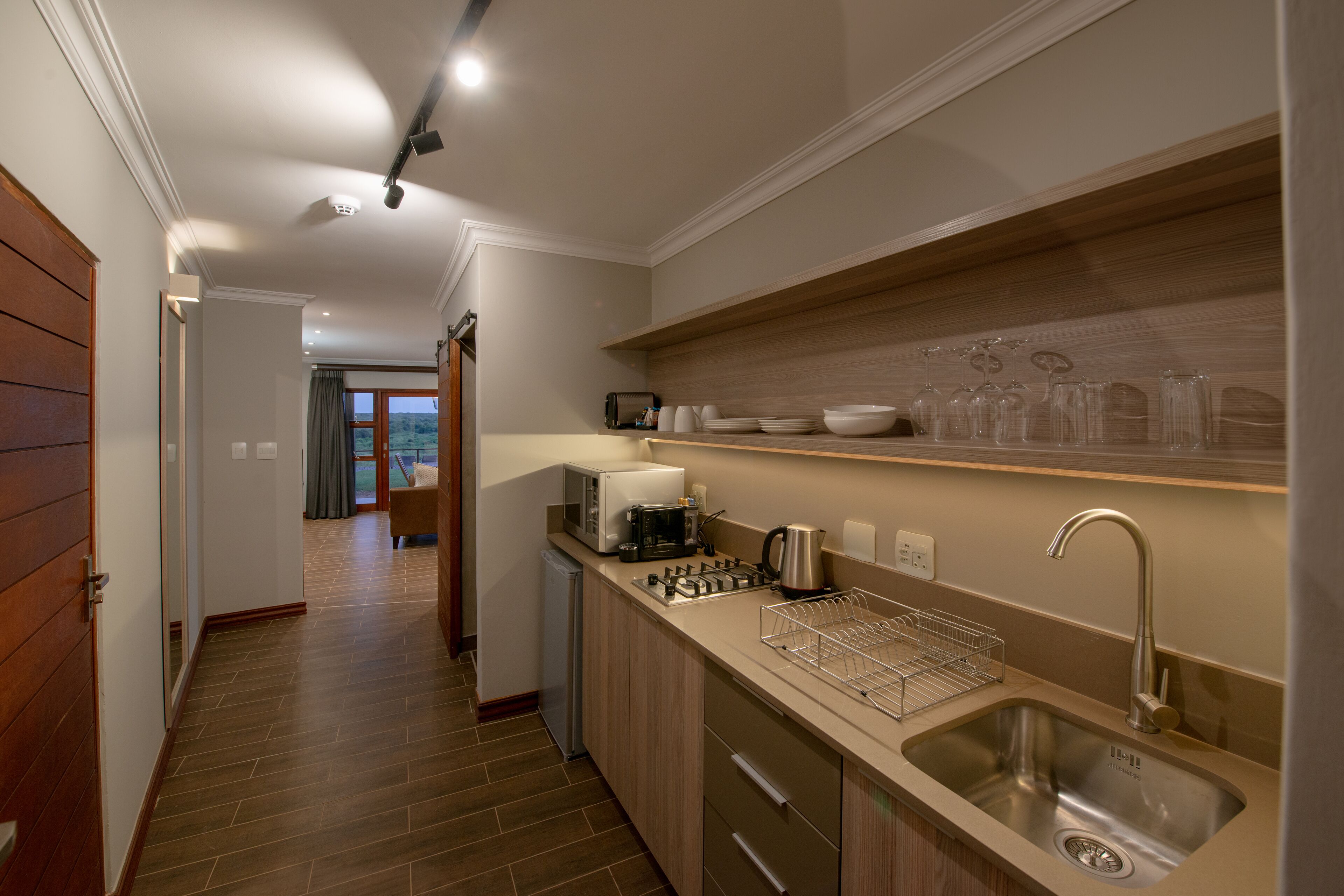 Una cocina moderna con un lavamanos de acero inoxidable, un horno empotrado y una encimera con cafetera y tostadora.