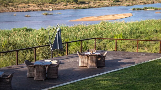 A deck with wicker furniture overlooking a river.