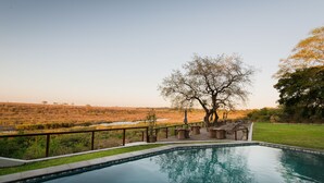 A swimming pool with a view of a grassy area and trees.