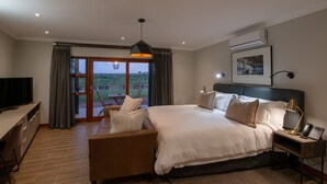 A modern hotel room with a large bed, a desk, a chair, and a view of the outdoors.