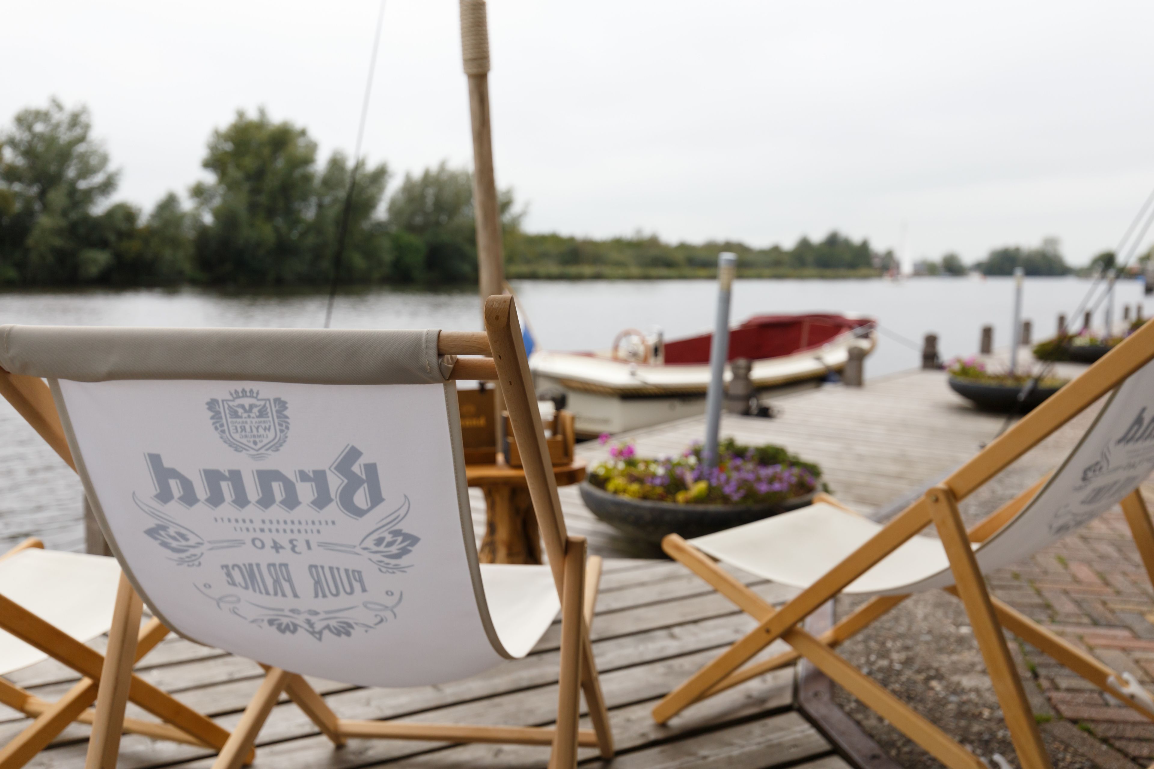A wooden dock with a canvas chair labeled "Pinnacle" and a boat in the background.