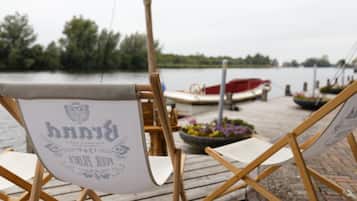 A wooden dock with a canvas chair labeled "Pinnacle" and a boat in the background.