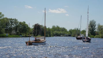 A calm lake with sailboats and a dock in the background.