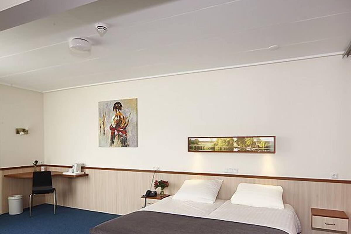 A hotel room with a large bed, a desk, and a chair.