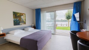 A hotel room with a bed, a desk, a chair, a TV, and a painting.