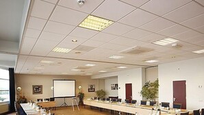 A conference room with a long table, chairs, a projector screen, and a whiteboard.