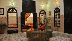 A Moroccan-style interior with a central coffee table, ottomans, and a patterned floor. - Riad Baddi (Salé)