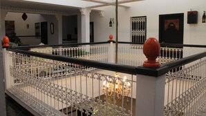 A grand interior with ornate white railings, a chandelier, and a decorative balustrade. - Riad Baddi (Salé)