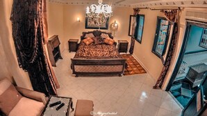 A bedroom with a large bed, a chandelier, and a view of a balcony. - Riad Baddi (Salé)