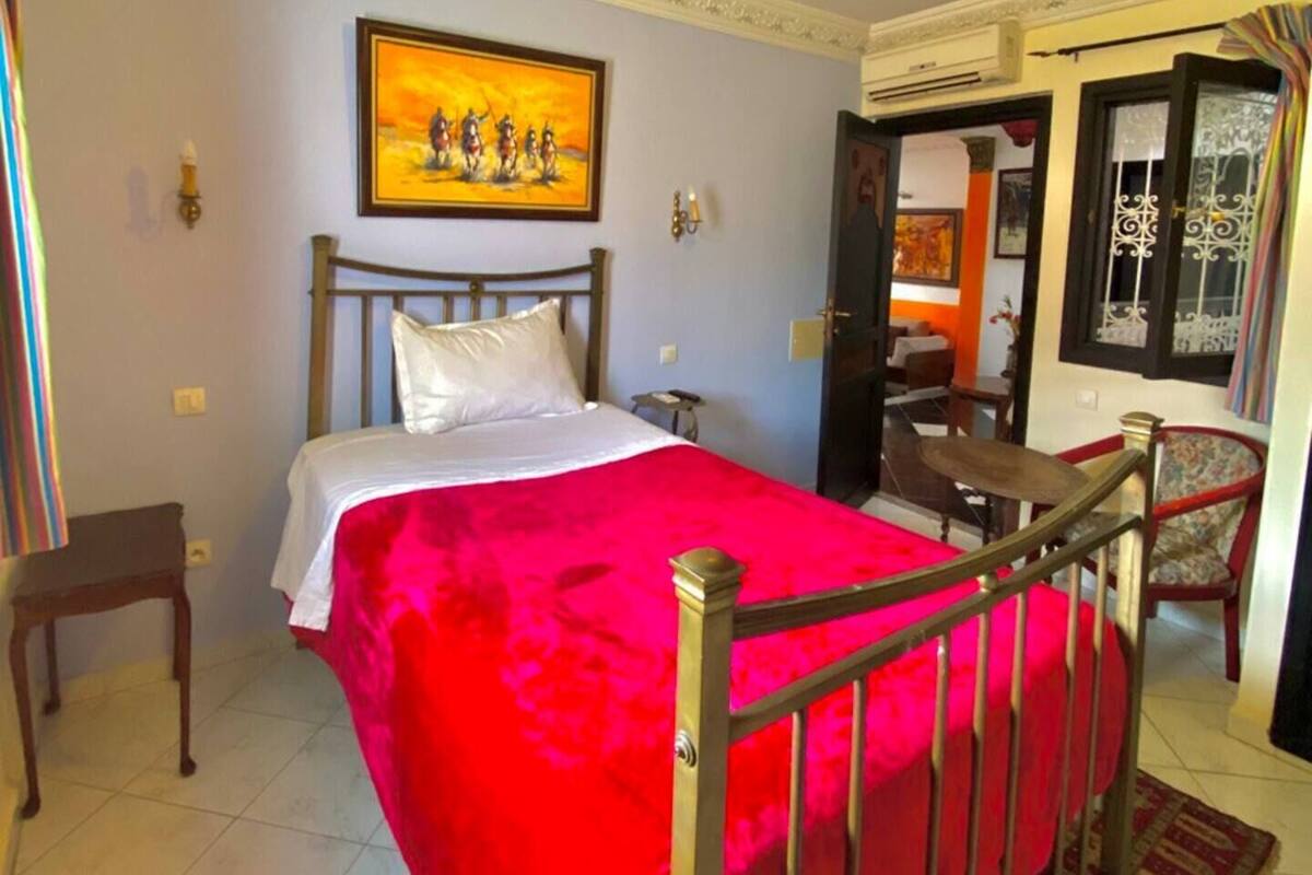Una habitación de hotel con una cama, un cuadro en la pared, un escritorio y una silla.