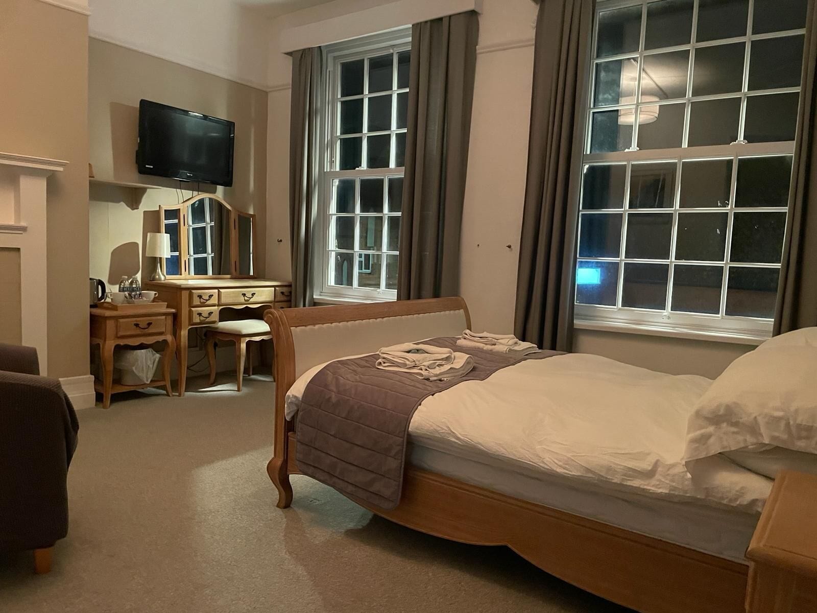 Une chambre d’hôtel comprenant un lit, un bureau avec une chaise, une télévision et de grandes fenêtres.